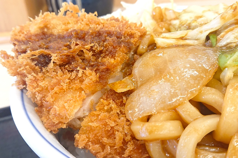 チキンカツの上にどっさり盛られた焼きうどん
